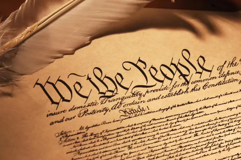 Photo of the constitution on parchment with a quill pen.